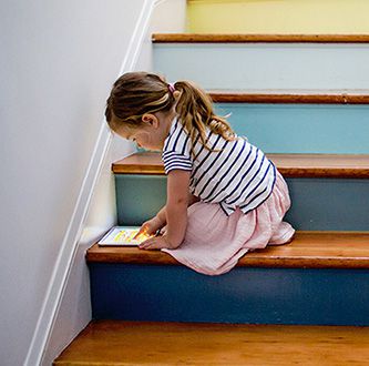 Girl playing with tablet on a staircase.