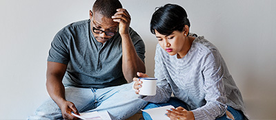 Two people sitting on a floor, looking at bills